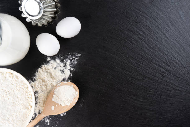 istock Baking ingredients flour, eggs, milk, bakeware on black slate background with copy space 1443798122