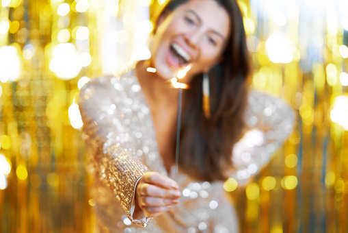Young woman holding sparkle over gold background. High quality photo