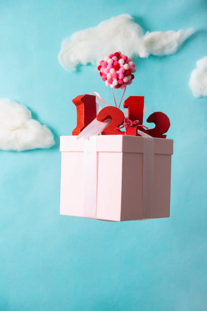 istock Miniature models, balloons dangling from gift boxes and red number blocks 1443799734