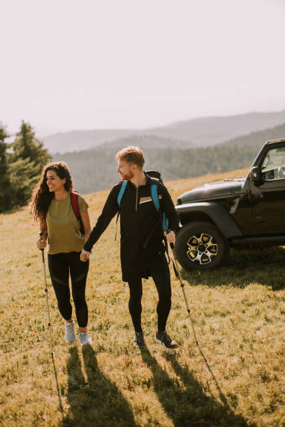 istock Smiling couple walking with backpacks over green hills 1443801595