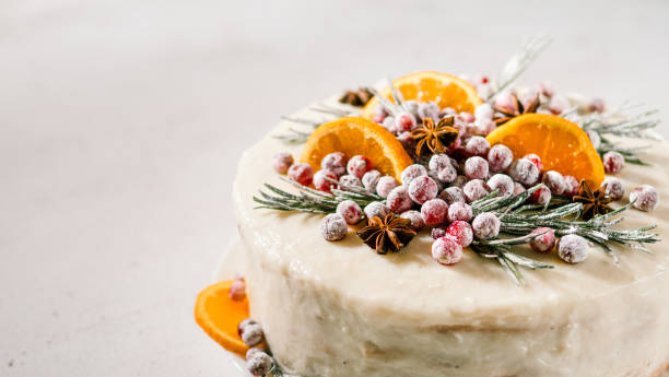 Cristmas cake decorated rosemary cranberries Winter homemade cake on white marble background. White cream christmas cake decored rosemary, cranberries, star anise and oranges slices. Copy space. Vertical ice pie photography stock pictures, royalty-free photos & images