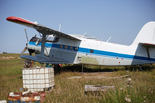 An An-2 plane is on the ground, an old plane in the neighborhood lies all sorts of junk.
