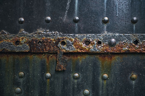 Closeup of an old green wooden front door, with brass mail slot.