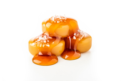 Front closeup view of a three salted caramel candies dripping caramel sauce isolated on white background