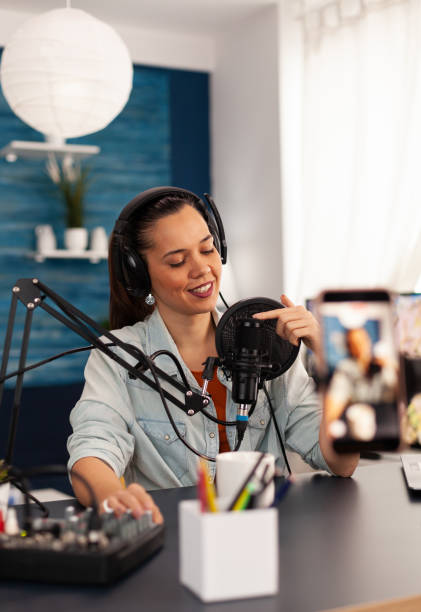 istock Vlogger on air during her podcast channel using mixer and professional microphone 1443808647