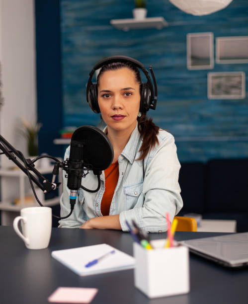 istock New media star looking at camera while talking into microphone during video podcast 1443809554
