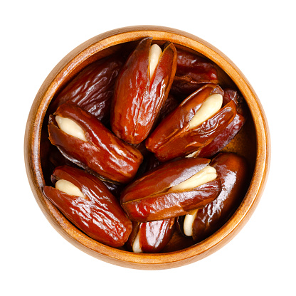 Almond-stuffed dates, in a wooden bowl. Sun dried Deglet Nour dates, cut open and pitted, then filled with whole blanched almonds. A delicious sweet snack or dessert, originally from North Africa.