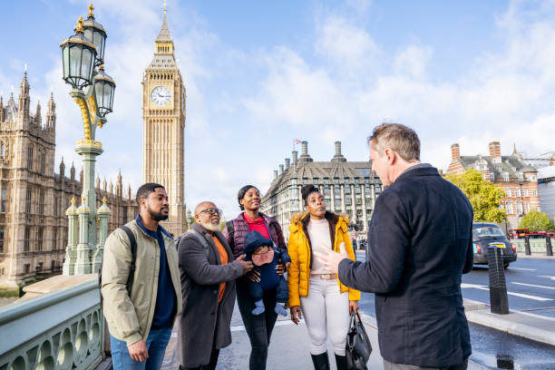 guide und reisegruppe auf der westminster bridge in london - english culture talking men listening stock-fotos und bilder