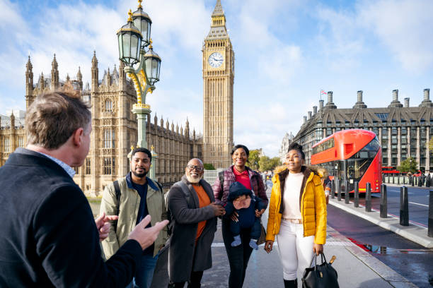 ロンドンのガイド付きツアーを楽しむ休暇中の黒人家族 - english culture talking men listening ストックフォトと画像