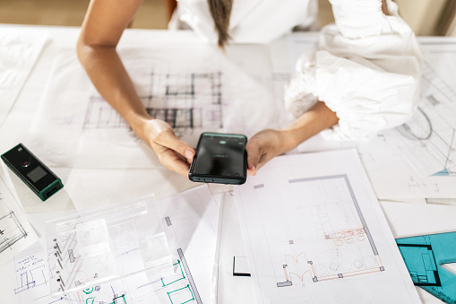 Young woman architect sitting in her office and drawing, preparing and analyzing architectural plans