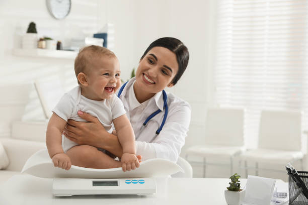 giovane pediatra che pesa il piccolo bambino carino in clinica. spazio per il testo - women smiling body cheerful foto e immagini stock