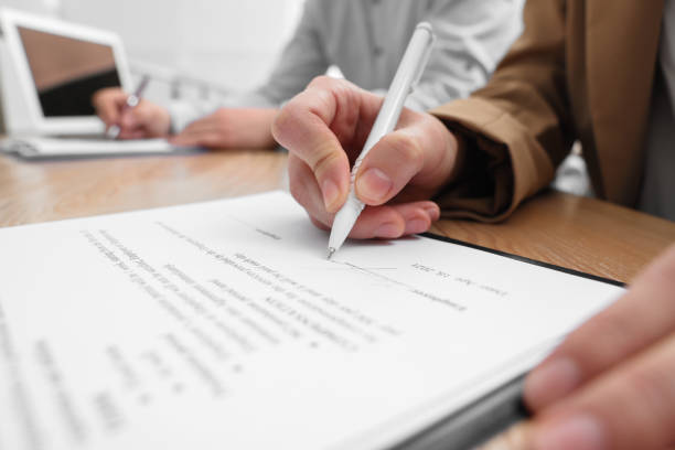 istock Woman signing contract at table in office, closeup. 1443823020