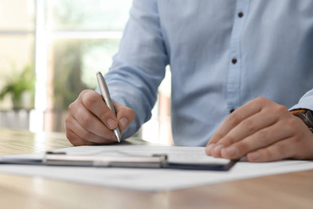 istock Man signing contract at table in office, closeup. 1443823901