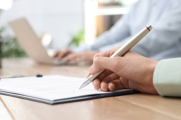 istock Woman signing contract at table in office, closeup. 1443823951