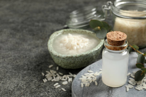 istock Glass bottle with rice water and grains on grey table. Space for text 1443824798