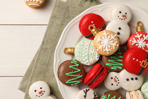 istock Beautifully decorated Christmas macarons on white wooden table, flat lay 1443824890