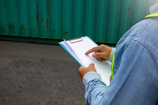 A close up of a male worker examining on the report at a container shipping company