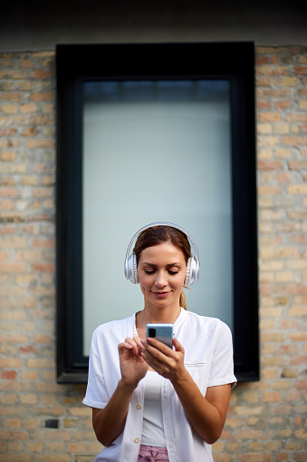 Portrait of a woman enjoying music in the city on her mobile phone