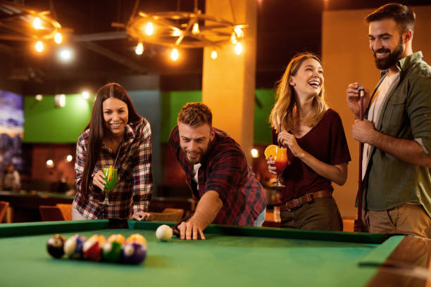 Group of friends having fun while playing pool in a local pool hall