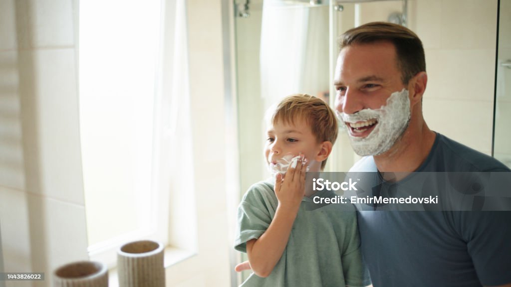 Father teaching his son how to shave A father teaching his little son how to shave in the bathroom at home Adult Stock Photo