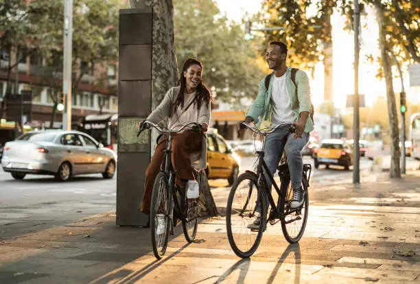 Photo of African american couple cycling in the city. Students laughing.