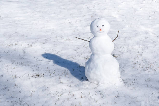 istock Snowman on white background. Green grass growing. First snow. 1443827841