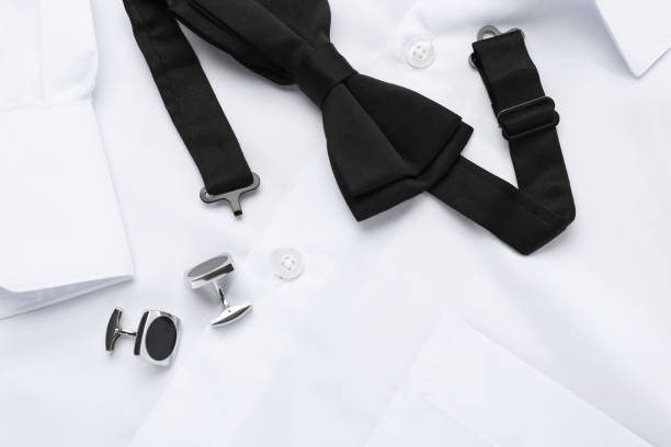 istock Stylish black bow tie and cufflinks on white shirt, top view 1443829001