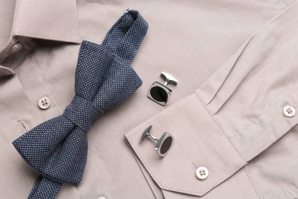 istock Stylish blue bow tie and cufflinks on beige shirt, top view 1443829276