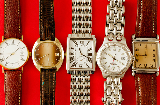 Color image depicting vintage chronograph wristwatches on a red background.