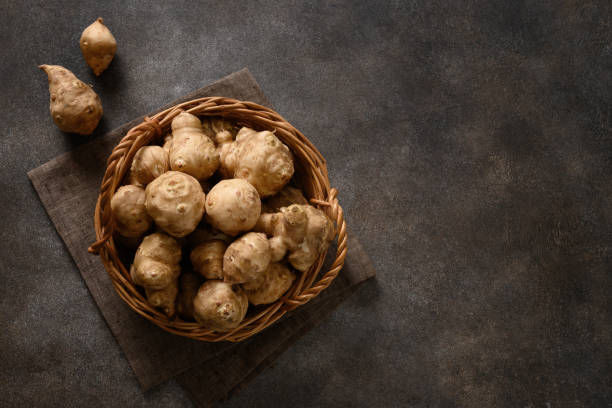 istock Jerusalem artichoke root, sunchokes on dark brown. 1443830275