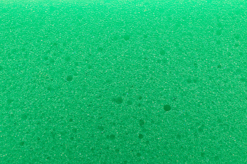 Green cleaning sponge as background, top view