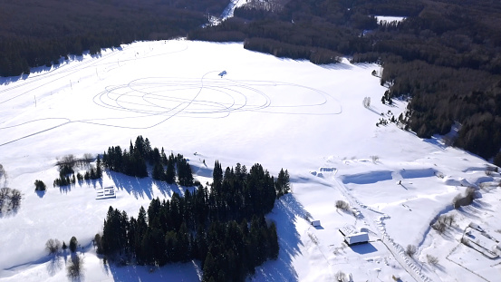 Winter bird's-eye view. Clip. Snowy winter sunny forest near residential small houses and large snowdrifts .