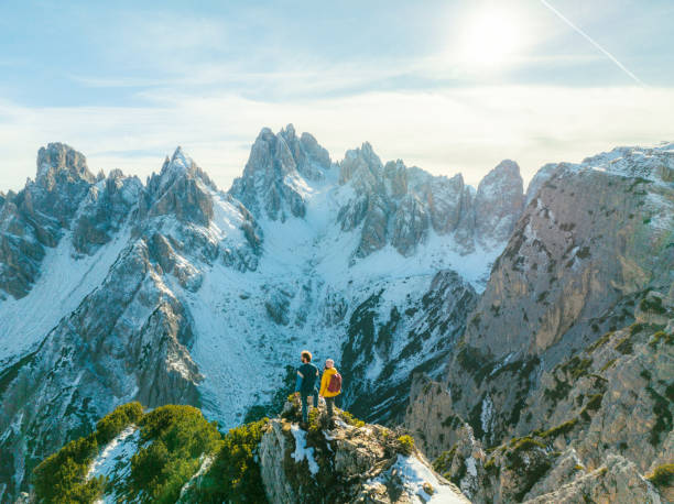 vista aérea de un hombre y una mujer de pie sobre el fondo de los dolomitas nevados - natural landmark winter season mountain peak fotografías e imágenes de stock