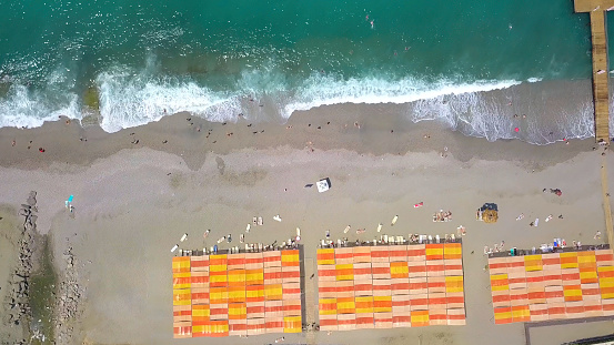 Bird's-eye view. Clip. A huge ocean next to the beach where people swim and relax with sand and a small bridge to jump on