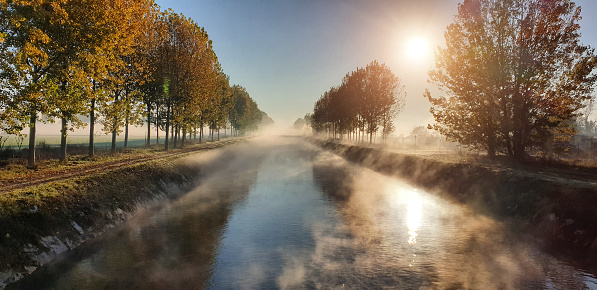 Fog and sun in autumn season on the river - Panoramic view from Vacchelli river channel (Lombardy - Italy)