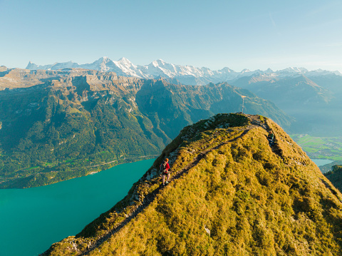 Aerial view of young man in red sweater hiking  on the background of Interlaken in Swiss Alps