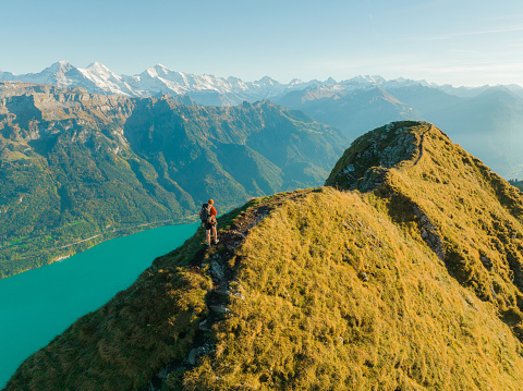 Aerial view of young man in red sweater hiking  on the background of Interlaken in Swiss Alps