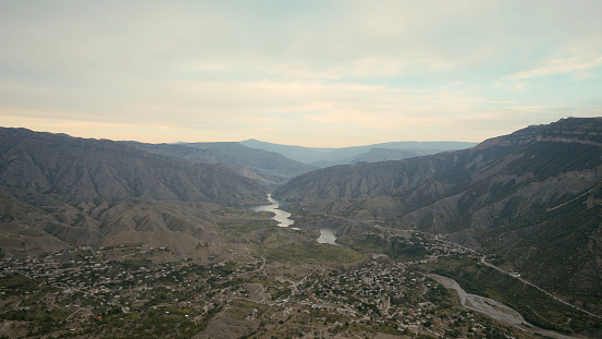 Aerial view of a bending river flowing above green high hills covered by haze. Action. Curving beautiful river and a picturesque valley, Indonesia