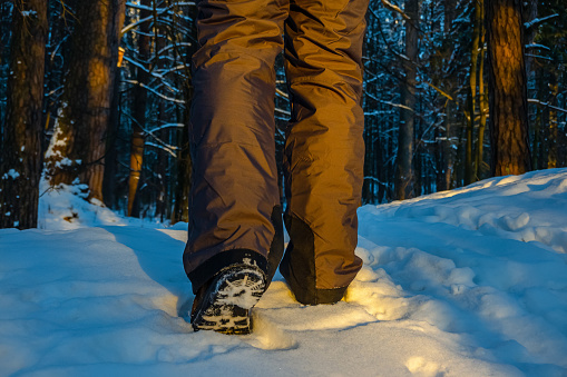 Close up of hiker shoes walking on the snow in the forest. Exploring woodland in winter time.