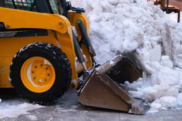 Photo of Heavy duty earth mover cleaning snow off the sidewalks after blizzard.