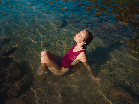 female tourist wearing swimsuit relaxing in sea at beach near ancient city Phaselis, Kemer Antalya province Turkey. ancient port city with beach and ruins of ancient Roman baths, theaters, aqueducts