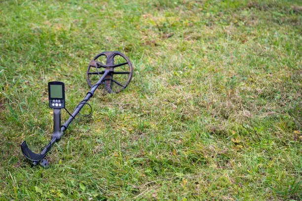 Photo of Metal detector laying outdoors on the grass. Close up electronic treasure finder.