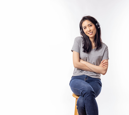 Portrait smiling young asian woman with crossed arms Happy asia girl posing with crossed arms and looking at camera white background copy space Confident female get happy and feel relax She wear jeans