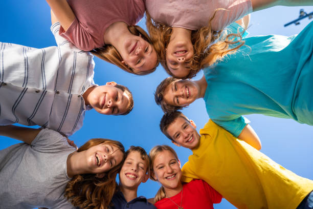 istock Group of embraced children standing in circle against blue sky 1443848330