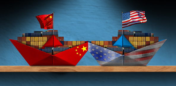 China and United States Trade War Concept. Collision of two cargo container ships with the chinese and United states of America flag. Two paper boats on a wooden shelf.