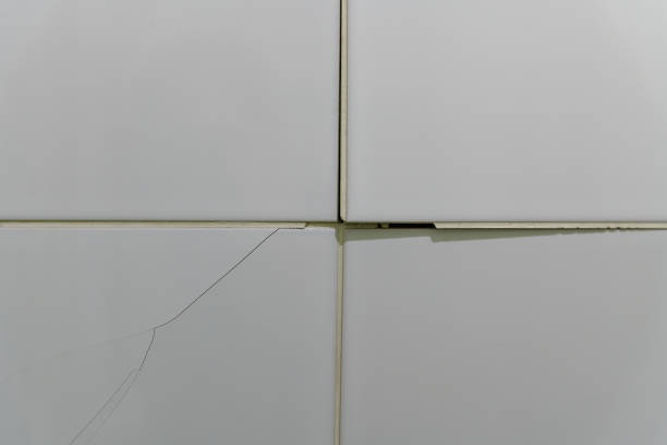 istock Cracked, broken bathroom wall tiles or panels - closeup view. 1443853549
