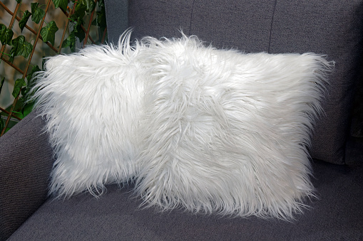 Decorative fluffy white pillows standing in corner of a couch