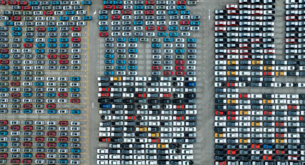 Aerial view of new cars stock at factory parking lot. Above view cars parked in a row. Automotive industry. Logistics business. Import or export new cars at warehouse. Big parking lot at port terminal stock photo