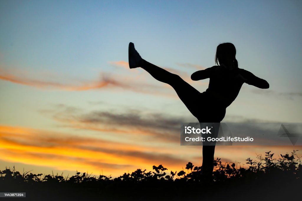 Kickboxing Silhouette of a female fighter in high kick position. Unrecognizable young woman. 20-24 Years Stock Photo