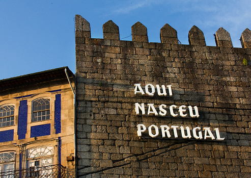 Portugal was born here, portuguese language sign on the remains of medieval walls. Toural square, Guimarães, Portugal